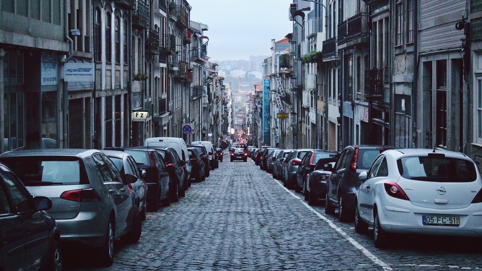 vehicles parked at sidewalk between buildings