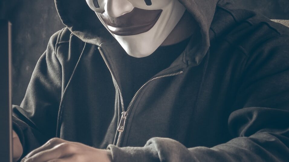 a person wearing a mask using a laptop