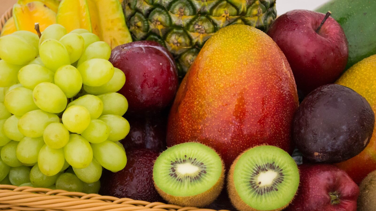 red apple fruit beside green apple and yellow fruit on brown woven basket