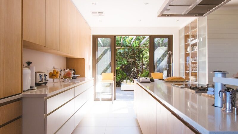 white wooden kitchen island and cupboard cabinets near glass panel door