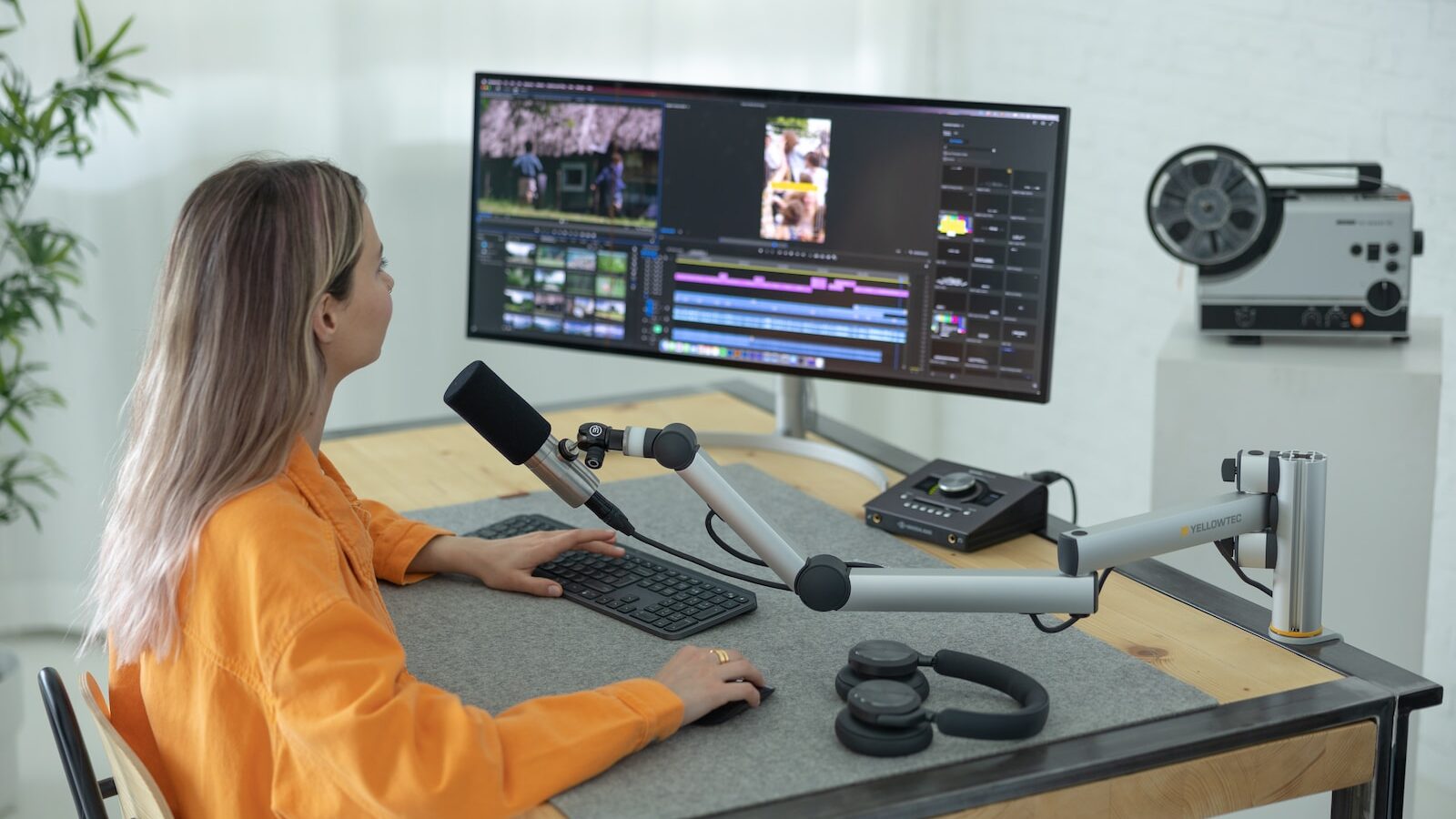 a person sitting at a desk with a computer and a microphone