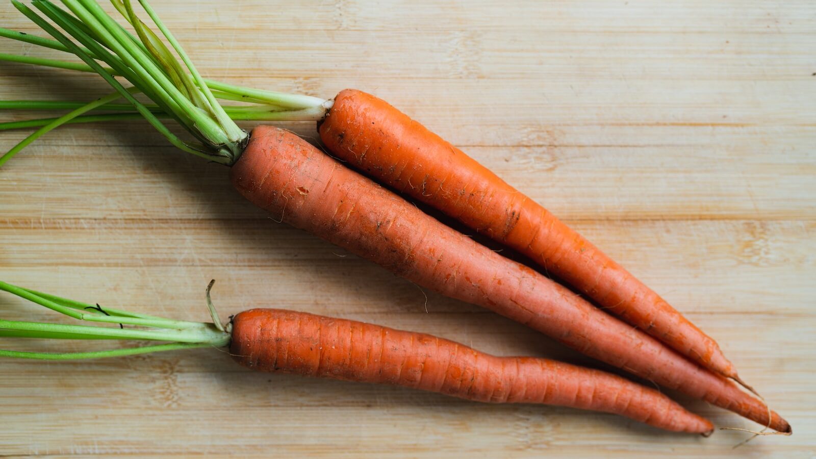 3 carrots on brown wooden table