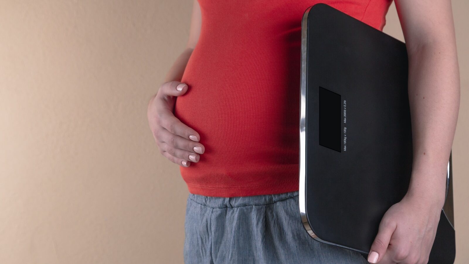 pregnant woman touching her belly and carrying a digital bathrooms cale