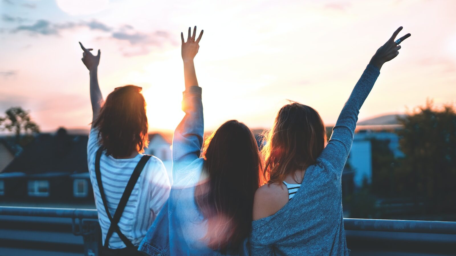 photo of three women lifting there hands 