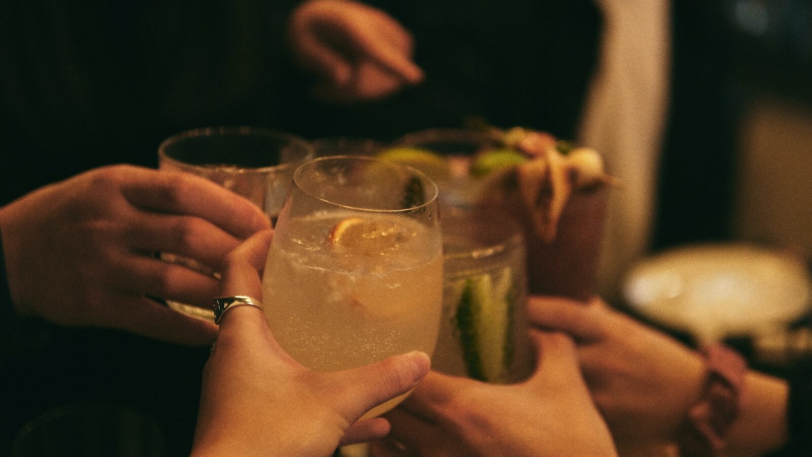 person holding clear drinking glass with yellow liquid